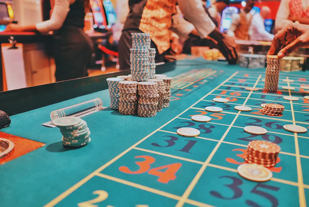 Casino table with poker chips stacked in piles, roulette bets marked with chips, and croupiers in uniforms handling chips in the background—a vibrant scene that’s among the top things to do in Madras OR for a thrilling night out.